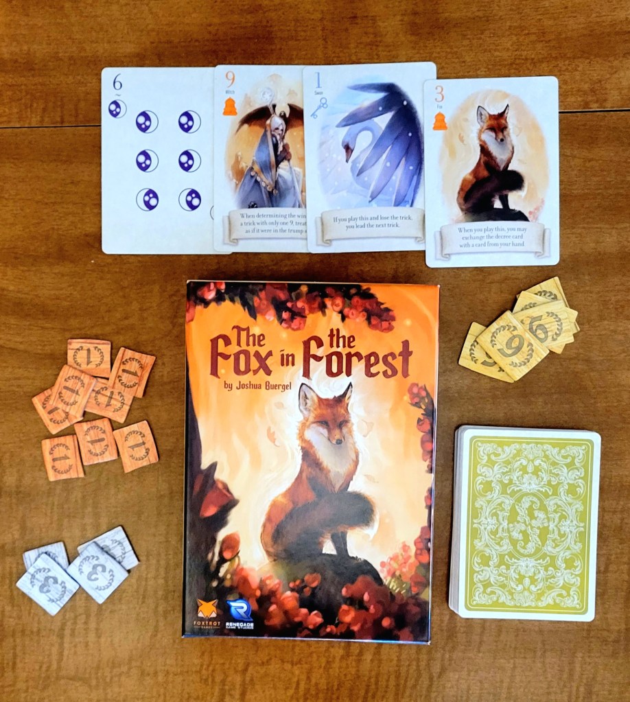 Game laid out on a table. In the center is the box, with a painting of a fox and the words "The Fox in the Forest by Joshua Buergel." Above the box are four cards. Left to right they show: six moon symbols, a person in a blue robe holding what could be a sword, a blue swan, and a fox. To the right of the box is a stack of yellow pieces with the number 6 on them, and a stack of light green cards with a white floral design. To the left of the box is a stack of orange pieces with the number 1 and blue pieces with the number 3.