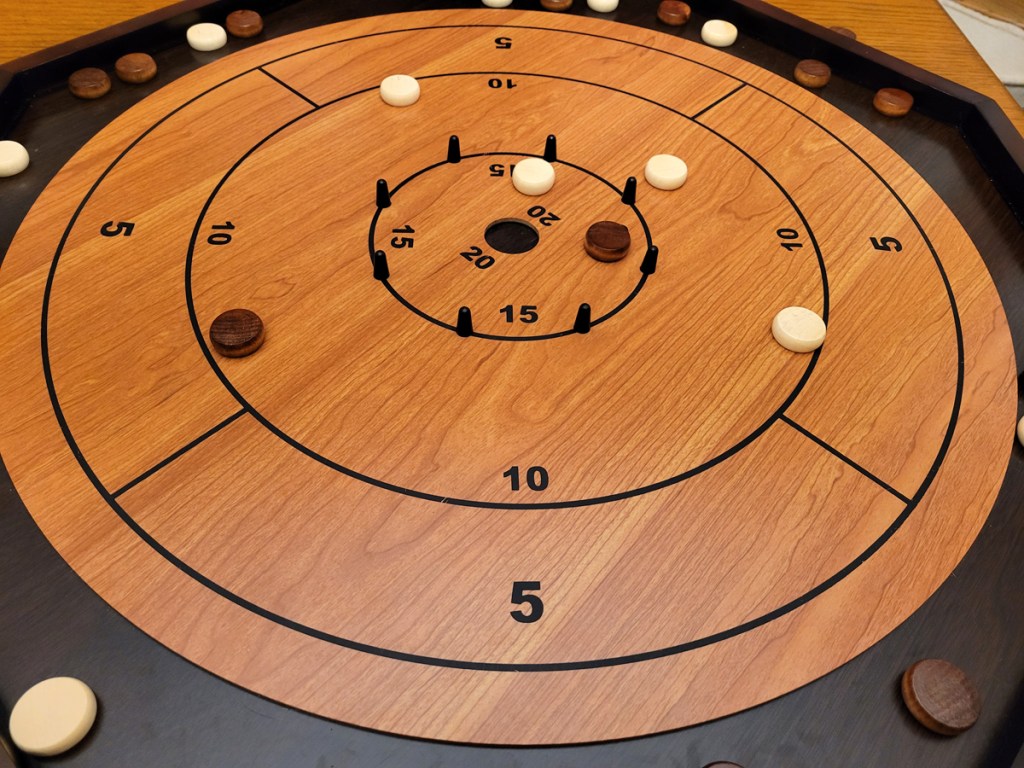 Photo of a crokinole board with both colors of pieces on the board ready for scoring.
