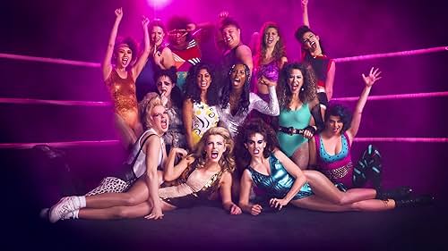 Image description:
Female 80s wrestlers in a ring with pink ropes and a purple light directly behind them
End image description